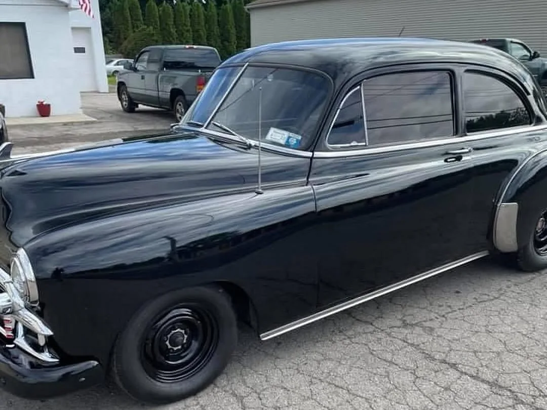 A black 1950s sedan in the lot