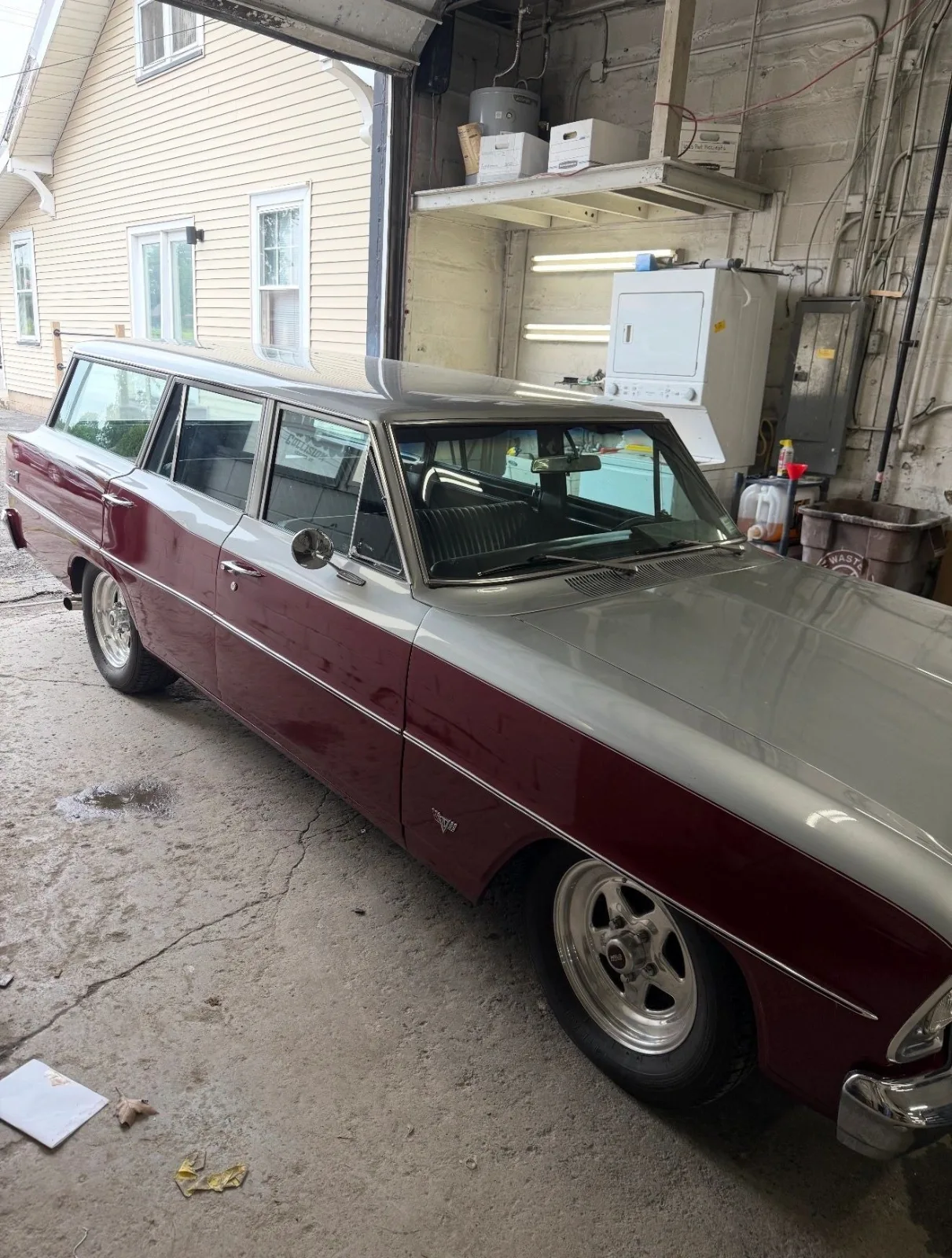 A restored Chevy wagon in two-tone silver and burgundy, parked in the shop